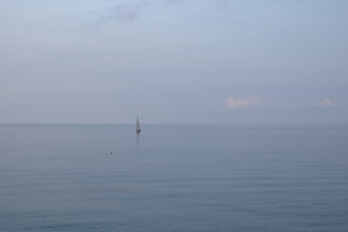Calm sea in the evening with sailboat offshore