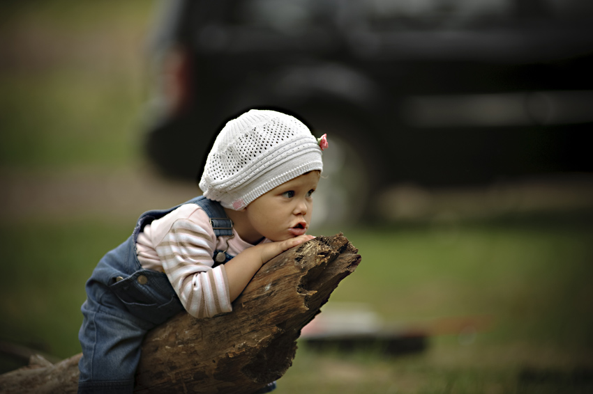 Porträt eines Mädchens auf einem Baumstamm