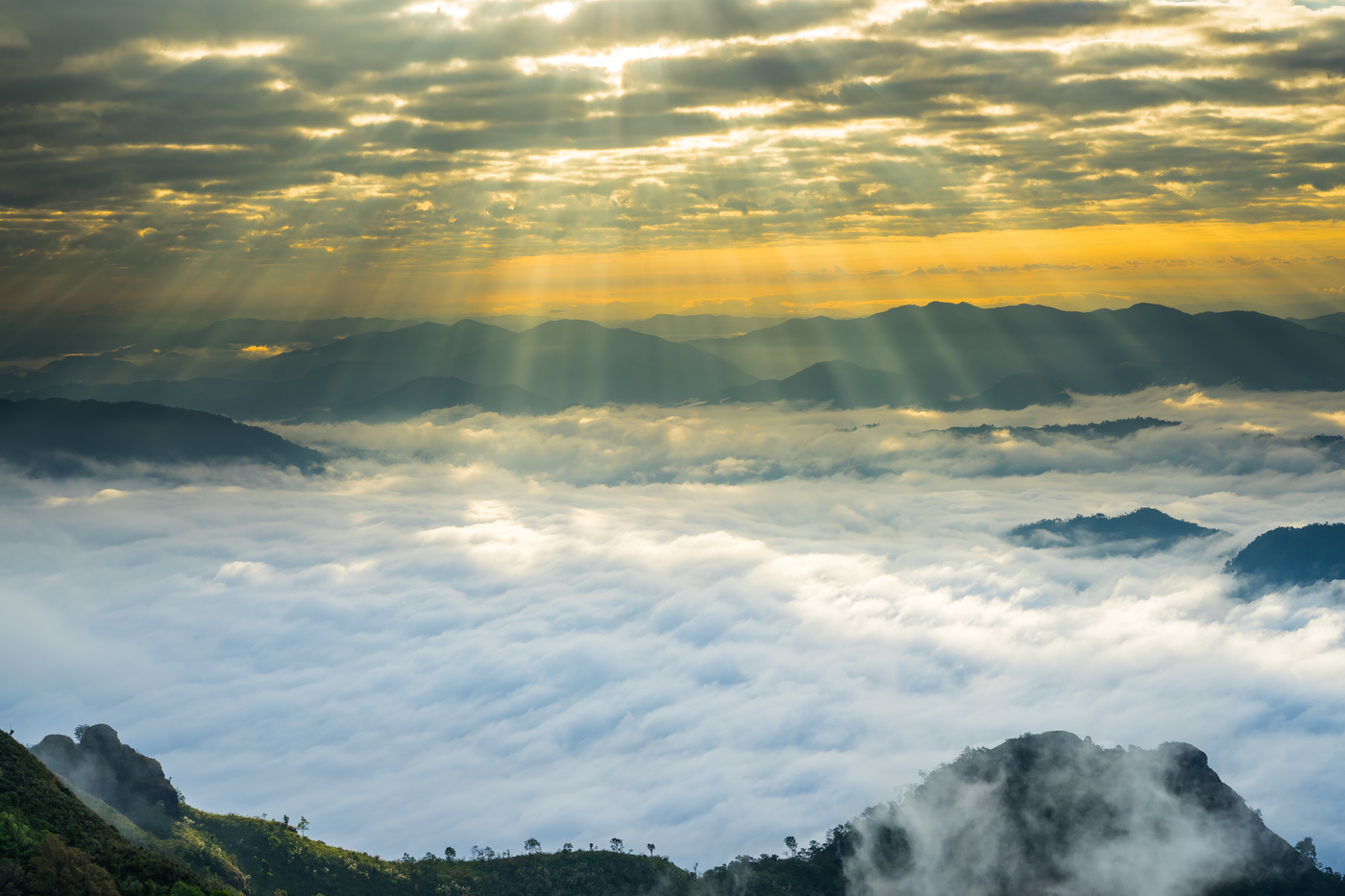 Crepuscular sun rays during sunrise over mist mountain